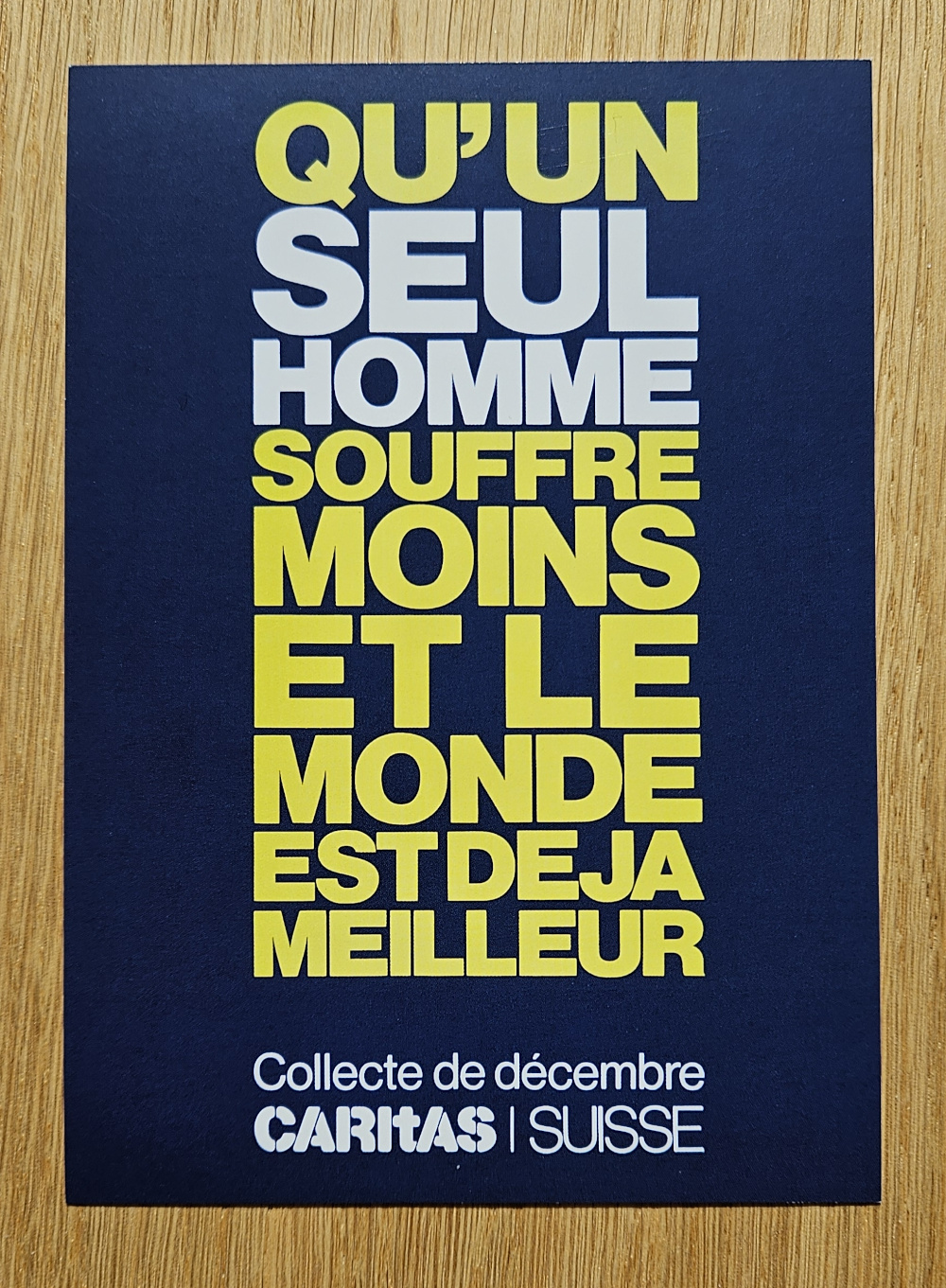 A postcard from Caritas Switzerland reading (translated from French) "May a single person suffer less - it's already a better world".